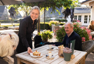 Camarera sirviendo pastel y café en la terraza de Wellness Lodge, Hof van Salland, Países Bajos.