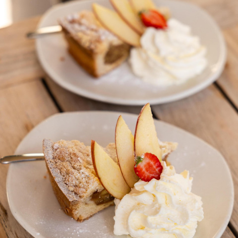 Due piatti con torta di mele, panna montata, fettine di mela e fragola presso Wellness Lodge, Hof van Salland.