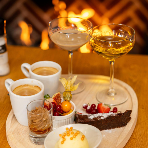 Lækker dessert og drikkevarer serveret foran en ildsted i Wellness Lodge, Hof van Salland, Nederlandene.