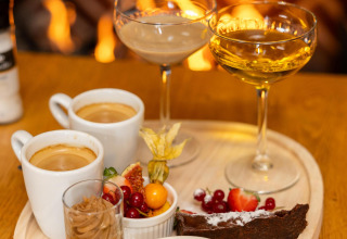 Postres y bebidas servidos frente a la chimenea en Wellness Lodge, Hof van Salland, Países Bajos.