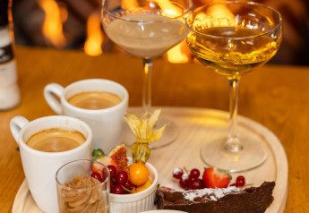 Postres y bebidas servidos frente a la chimenea en Wellness Lodge, Hof van Salland, Países Bajos.