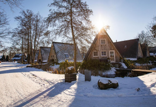 Día soleado de invierno en Wellness Lodge, Hof van Salland, con pequeñas casas y nieve en los Países Bajos.