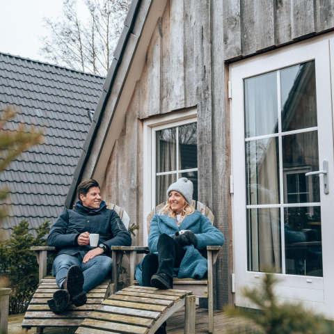 To personer nyder en afslappet stund udenfor Wellness Lodge ved Hof van Salland, Nederlandene om vinteren.
