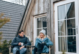 Dos personas se relajan afuera de la casa Wellness Lodge en Hof van Salland, Países Bajos, un día frío.