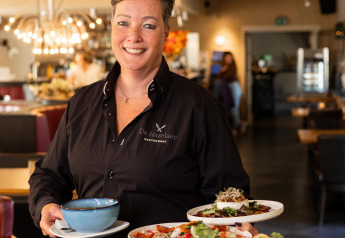 Cameriera sorridente serve piatti colorati al ristorante De Hazelaer, Wellness Lodge, Hof van Salland, Paesi Bassi.