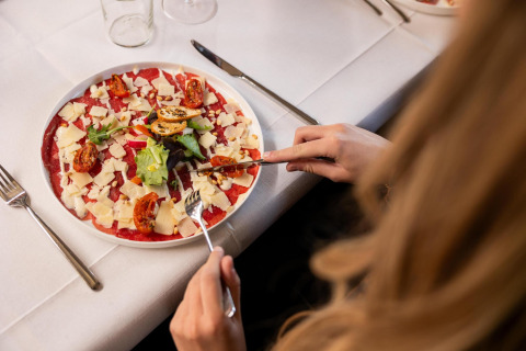 Persona comiendo carpaccio con queso, tomates y hojas verdes en Wellness Lodge en Hof van Salland, Países Bajos.