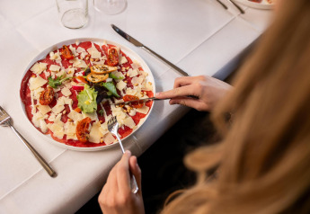 Persona comiendo carpaccio con queso, tomates y hojas verdes en Wellness Lodge en Hof van Salland, Países Bajos.