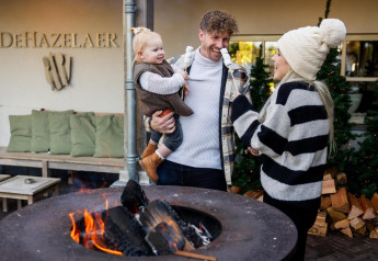 Familia disfruta junto al fuego frente a Wellness Lodge en Hof van Salland, DeHazelaer, Países Bajos.