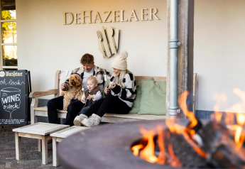 Familia con perro disfruta del exterior cálido junto al fuego en Wellness Lodge, Hof van Salland, Países Bajos.
