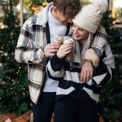 Couple savourant un chocolat chaud près des sapins à Wellness Lodge, Hof van Salland, Pays-Bas en hiver.