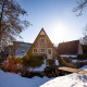 Met sneeuw bedekte tiny house Wellness Lodge in Hof van Salland, Nederland, met bomen in de winterzon.