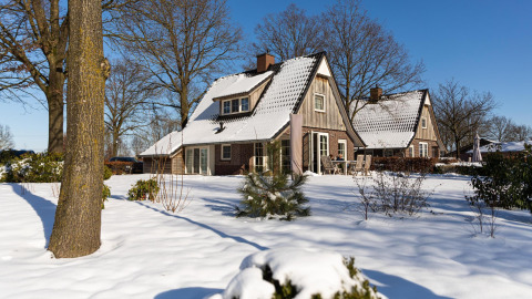 Tiny house chiamata Wellness Lodge a Hof van Salland, nei Paesi Bassi, coperta di neve sotto il sole.