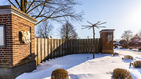 Entrée du Hof van Salland aux Pays-Bas, couverte de neige, avec des piliers en brique et des arbres derrière.