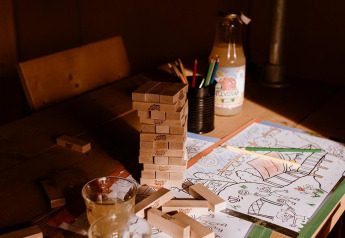 Jenga-blokken, kleurpotloden, sapglazen en kleurplaten op een houten tafel in een safaritent.