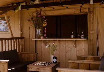 Interno di tenda safari glamping con mobili in legno e fiori a Holiday park Eigen Wijze nei Paesi Bassi.