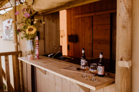 Bancone di legno in tenda glamping safari al Holiday park Eigen Wijze, Olanda, con birra e fiori.