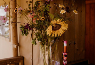 Jarrón con flores silvestres en una estantería de madera en una tienda glamping en Holiday park Eigen Wijze, Países Bajos.