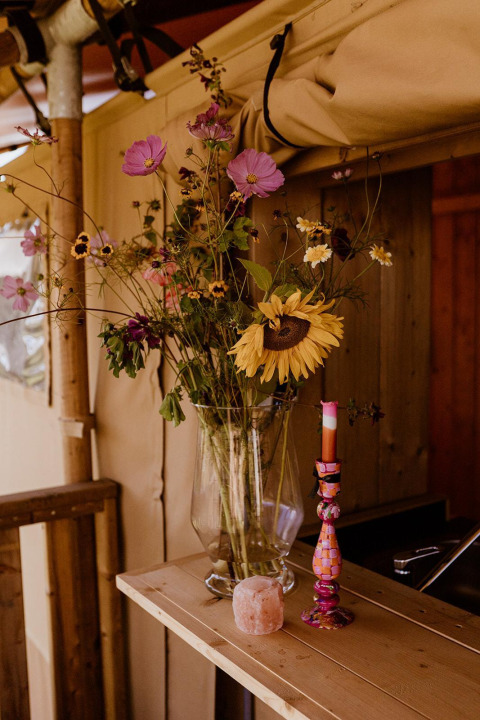 Vase med vilde blomster på træhylde i et safari glamping telt på Holiday park Eigen Wijze, Holland.