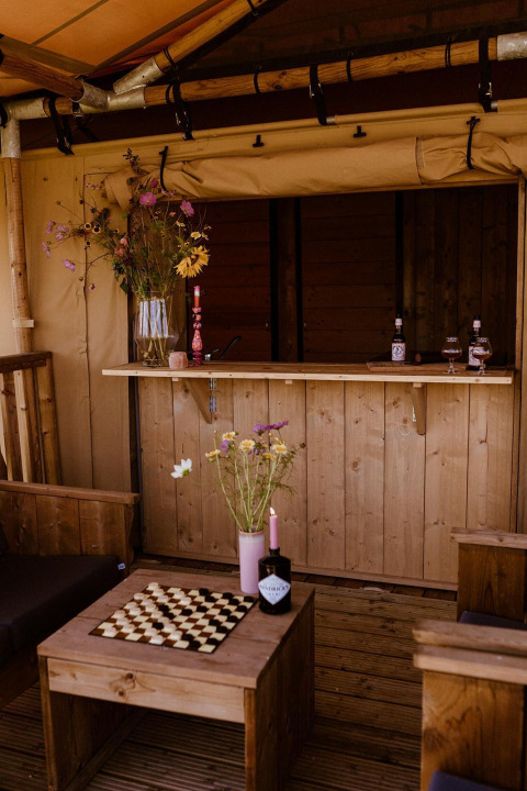 Tenda safari glamping al Holiday park Eigen Wijze nei Paesi Bassi, arredi rustici in legno e fiori selvatici.