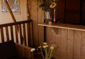 Tenda glamping safari accogliente con mobili in legno, fiori e scacchiera a Holiday Park Eigen Wijze.