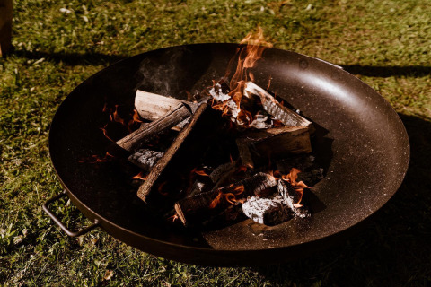 Hoguera ardiendo en un recipiente metálico junto a una tienda glamping en Holiday Park Eigen Wijze, Países Bajos.