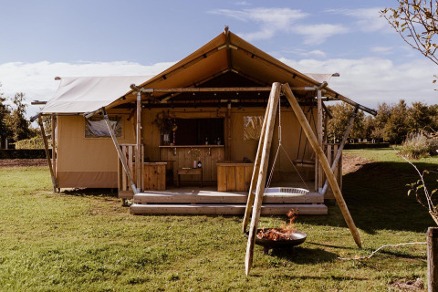 Safari glamping tent met houten terras, schommel en vuurkorf bij Holiday park Eigen Wijze in Nederland.