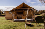 Safari glamping tent met houten terras, schommel en vuurschaal op Holiday park Eigen Wijze in Nederland.