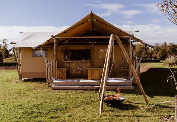 Tenda safari glamping con terrazza in legno, altalena e focolare presso Holiday park Eigen Wijze nei Paesi Bassi.