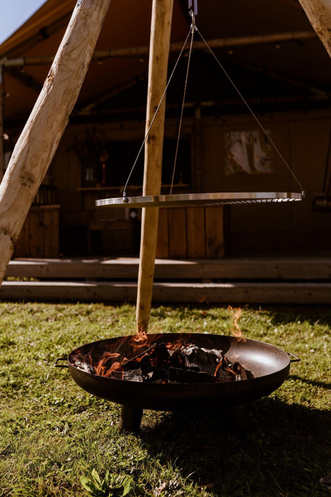 Feuerschale mit hängendem Grillrost bei einem Safarizelt im Glampingpark Eigen Wijze, Niederlande.
