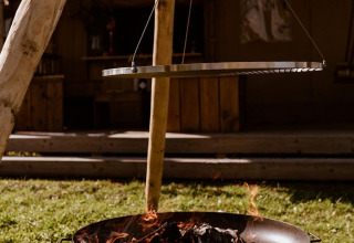 Feuerschale mit hängendem Grillrost bei einem Safarizelt im Glampingpark Eigen Wijze, Niederlande.