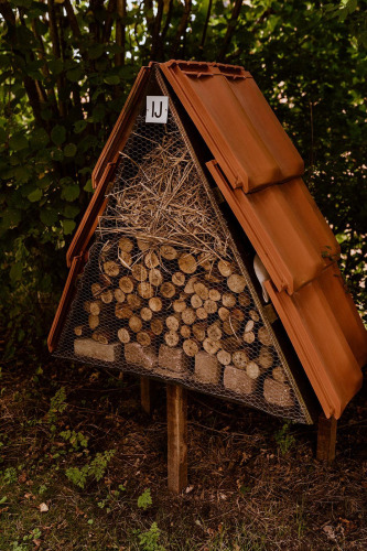 Hotel para insectos con madera y paja, visto junto a una tienda glamping en Holiday park Eigen Wijze, Países Bajos.