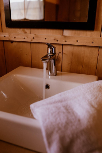 Grifo y lavabo en una tienda glamping de safari en Holiday Park Eigen Wijze, Países Bajos, con toalla.