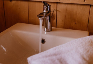 Robinet et lavabo dans une tente safari glamping au Holiday Park Eigen Wijze, Pays-Bas, avec serviette.
