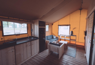 Vista interna di una tenda safari di lusso glamping con mobili in legno presso Holiday Park Eigen Wijze, Paesi Bassi.