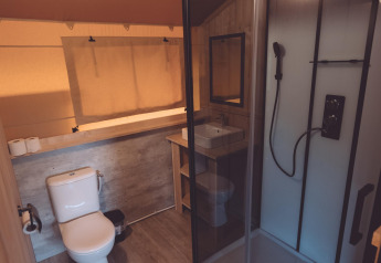 Badkamer in een glamping safaritent in Holiday Park Eigen Wijze, Nederland, met douche en toilet.