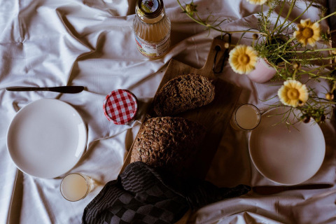 Mesa de desayuno con pan, jugo, platos y flores en una tienda glamping en Holiday park Eigen Wijze, Países Bajos.