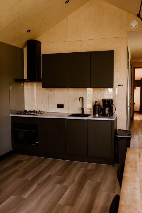 Moderne keuken in tiny house bij Holiday park Eigen Wijze, Nederland, met zwarte keukenkasten.