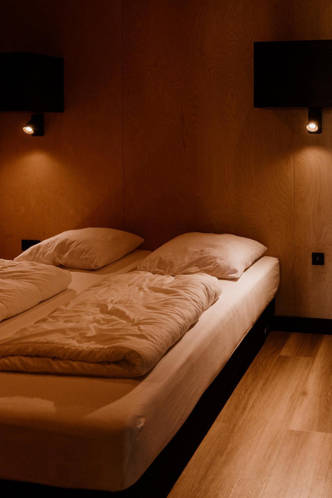 Dormitorio de una tiny house en Holiday park Eigen Wijze, Países Bajos, con cama y luz tenue.