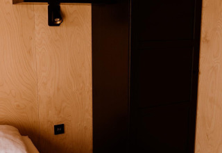 Moderne sort garderobe og skab i et kompakt soveværelse i Tiny house ved Holiday park Eigen Wijze, Holland.