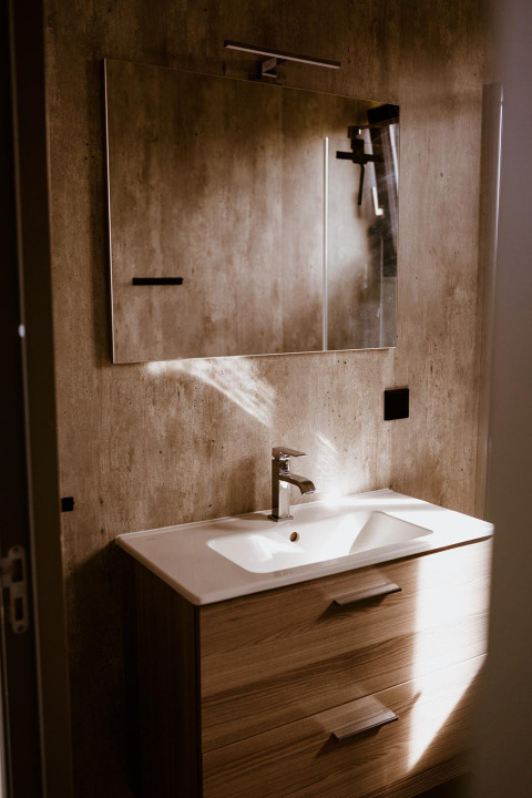 Moderne badkamer met houten wastafelmeubel, wasbak en spiegel in een tiny house op Holiday park Eigen Wijze, Nederland.