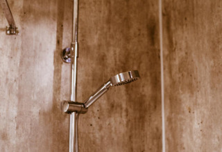Moderne Dusche im Badezimmer eines Tiny House im Holiday Park Eigen Wijze, Niederlande, mit Holzwand.
