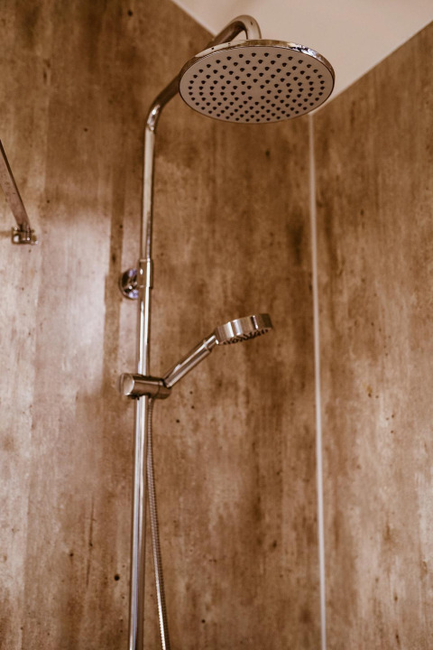 Moderne Dusche im Badezimmer eines Tiny House im Holiday Park Eigen Wijze, Niederlande, mit Holzwand.