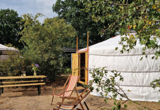 Vista exterior de una yurta mongola con sillas y banco en Zomerlicht Nature House, Países Bajos.