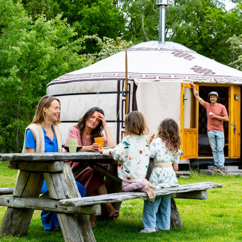 Familie nyder tid sammen ved et bord foran en mongolsk yurt hos Zomerlicht i Holland.