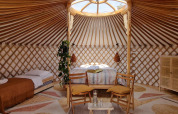 Licht, modern yurtinterieur met bedden en houten meubels, gefotografeerd in een gezellig natuurhuis.