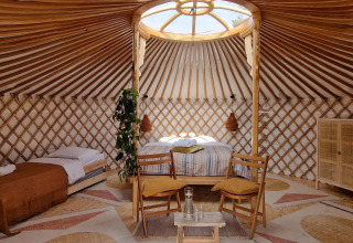 Interno luminoso di una yurta moderna con letti e mobili in legno, fotografato in una casa nella natura.