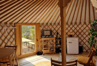 Indvendigt billede af en Mongolsk Yurt på Zomerlicht i Holland med et hyggeligt træinteriør.