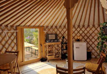 Interior of a Mongolian yurt at Zomerlicht in the Netherlands, featuring cozy wooden furniture and decor.