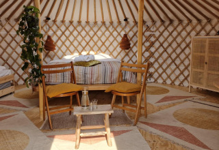 Acogedora casa de naturaleza con cama doble, cama individual, muebles rústicos y plantas en una yurta.