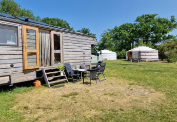 Foto esterna di una casa nella natura Mongoolse Yurt e due yurte a Zomerlicht nei Paesi Bassi in una giornata di sole.